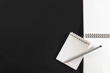 Üstten görünüm spiral defter ve kalem siyah yüzeyi