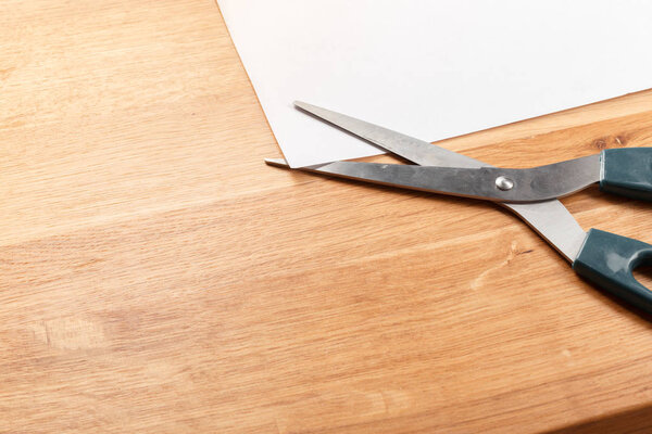 Scissors and blank paper on wooden table