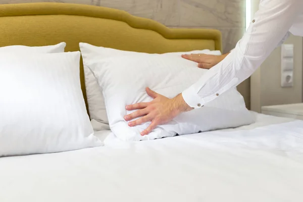 hotel staff setting up pillow on bed