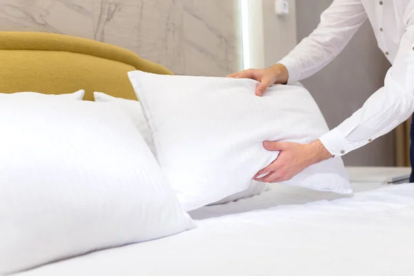 hotel staff setting up pillow on bed