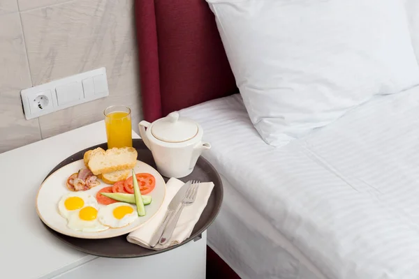 Fresh tasty breakfast by bed in hotel room