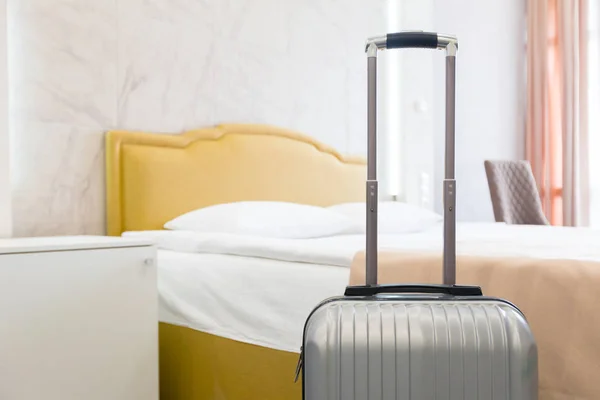 Grey luggage bag near bed in hotel room