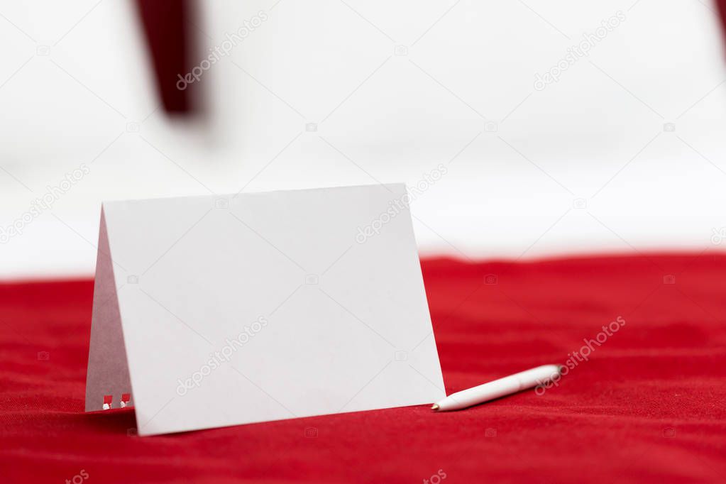 White note with pen on red tablecloth