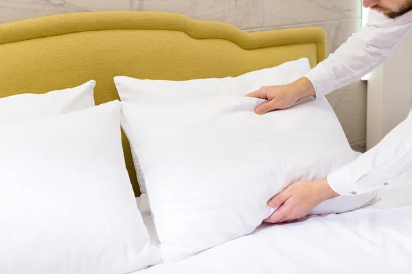 hotel staff setting up pillow on bed