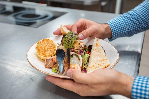 partial view of chef cooking in a restaurant kitchen