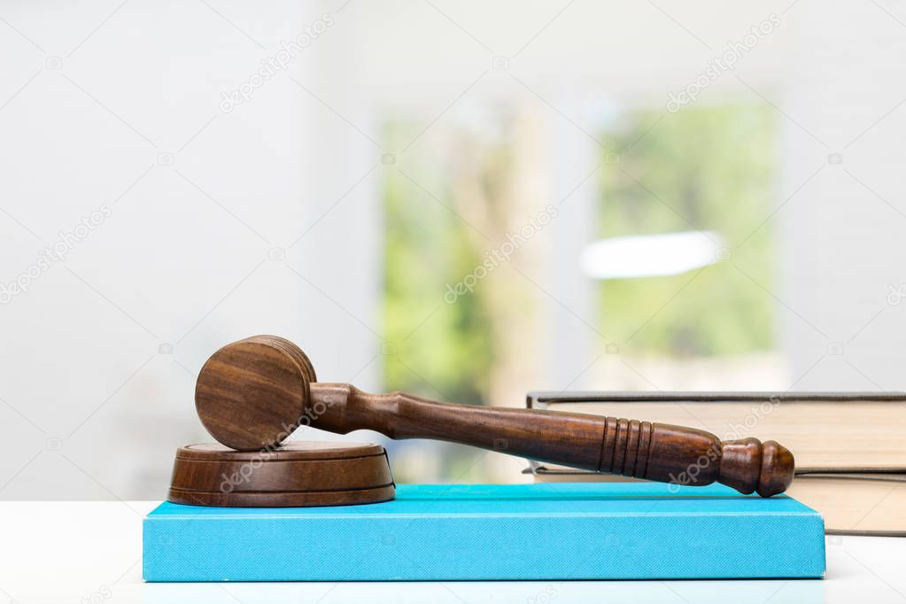 Wooden gavel and blue law books on wooden table