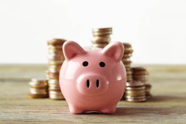 eski ahşap masa üzerinde para yığınları ile Piggy banka