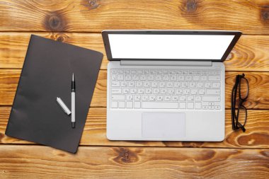 Laptop, defter üzerinde ahşap çalışma masası 