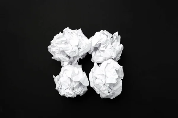 close up of balls of white paper on black background