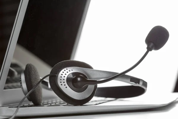 close up of call center support concept. headset on keyboard computer laptop