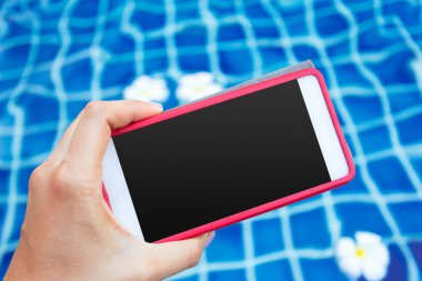 Smartphone ile havuz yakınındaki siyah perde. Tatil kavramı