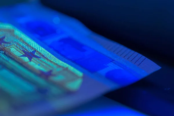 close up of checking money under ultraviolet lamp