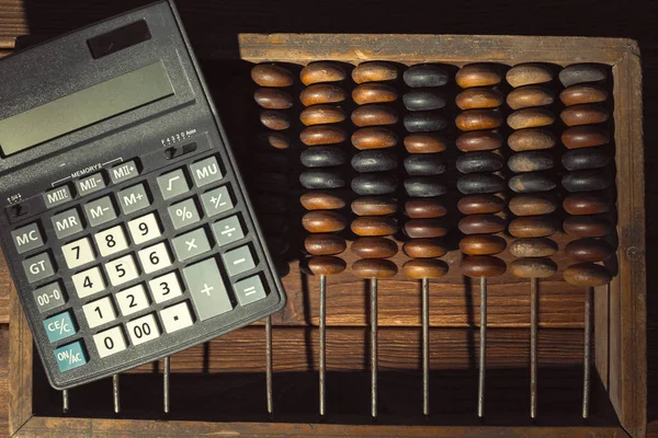 vintage abacus and modern calculator close up