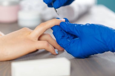 Kadın elleri güzellik salonunda manikür yaptırıyor.