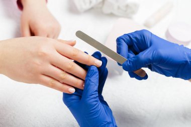 Kadın elleri güzellik salonunda manikür yaptırıyor.