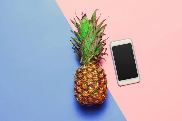 top view of pineapple and smartphone  on colored paper background