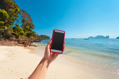 Kadın elini tut güzel taze deniz ve arka planda mavi gökyüzü ile beyaz cep telefonu