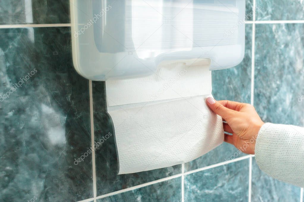 female hand taking paper from towel dispenser
