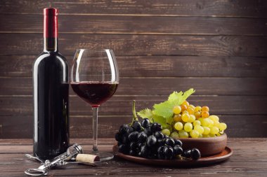Şarap şişesi ve ahşap masa üzüm