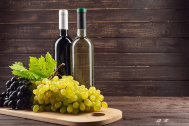Şarap şişesi ve ahşap masa üzüm