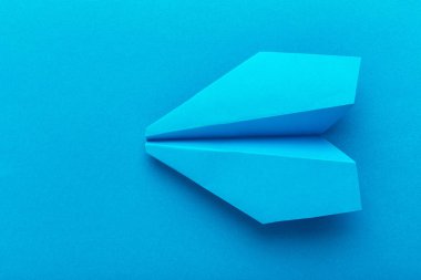 Düz bir kağıt uçak pastel mavi renk arka plan üzerinde yatıyordu