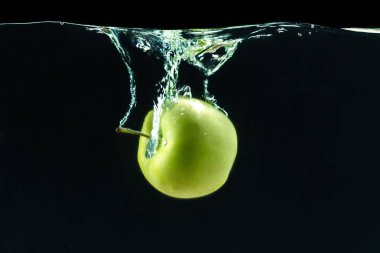 Siyah arka plan karşı su altında yeşil elma 
