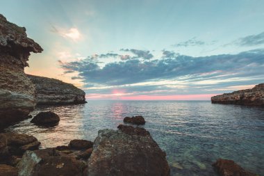 Parlak tatil hedef kumsalda gündoğumu ve deniz kayalıklarla arka plan