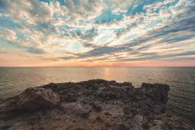 Parlak tatil hedef kumsalda gündoğumu ve deniz kayalıklarla arka plan