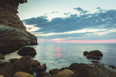 Parlak tatil hedef kumsalda gündoğumu ve deniz kayalıklarla arka plan