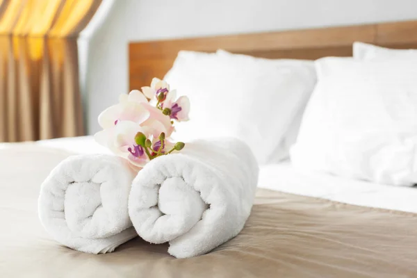 close up of towels and flowers on bed in hotel room