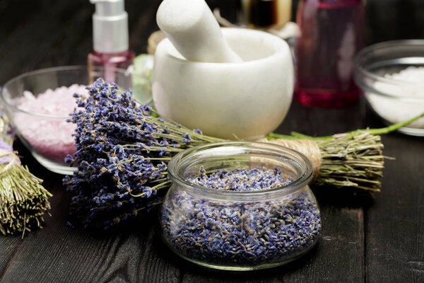 Ароматический состав лаванды, трав, косметики и соли на темной поверхности стола
