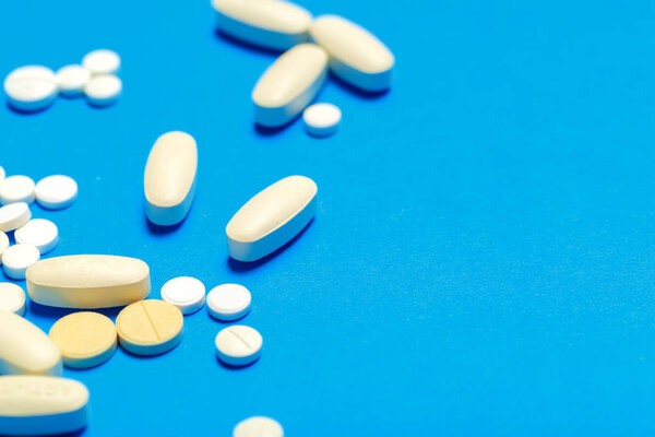 Таблетки разбросаны на синем фоне
