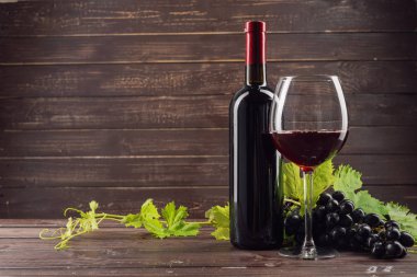 Şarap şişesi ve ahşap masa üzüm