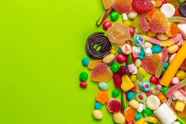 stock image Colorful candies on green background