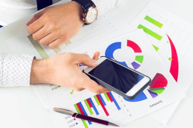 Ofis masası üzerinde akıllı telefon kullanan adam