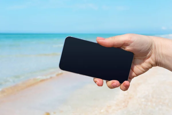 美丽的女人的手在海滩使用智能手机 — 图库照片