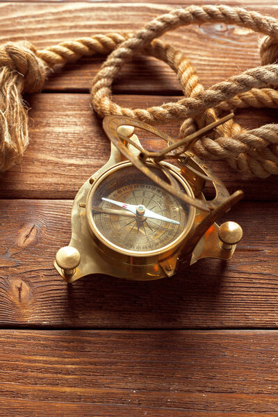  закрытие компаса и веревки на деревянном столе
