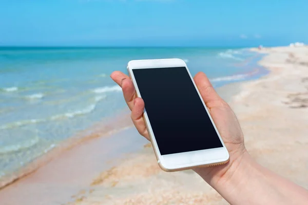 Beautiful woman\'s hand using smart phone at beach