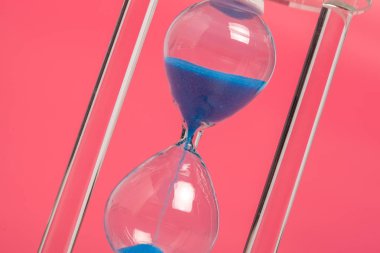 Kum saatinin pembe bir arka plan karşı yakın çekim