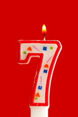 Kırmızı bir arka plan üzerinde renkli yanan Doğum günü mumu