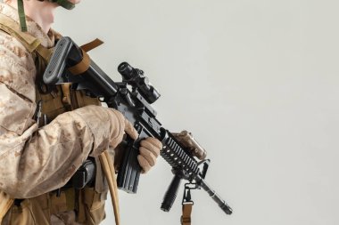 Kamuflajlı asker elinde tüfekle