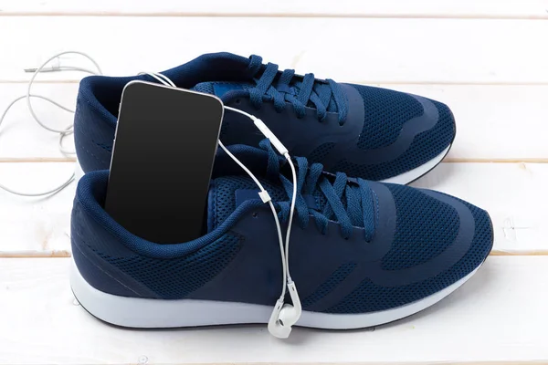 关闭运动鞋和手机与耳机在木制背景 — 图库照片