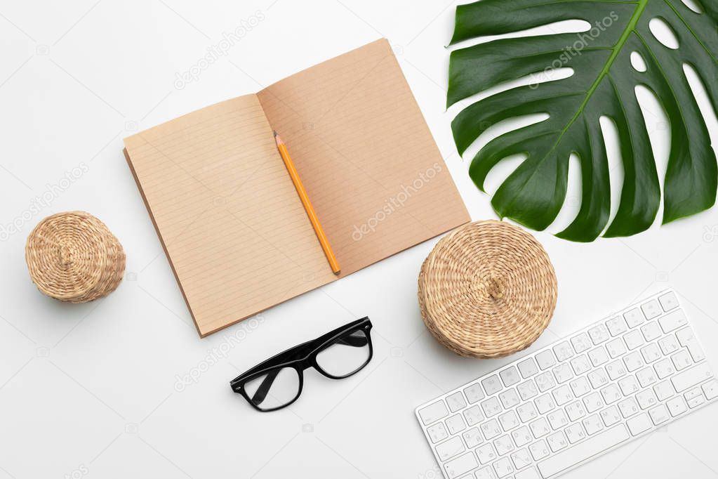 workspace with keyboard, palm leaf and accessories. Flat lay with copy space