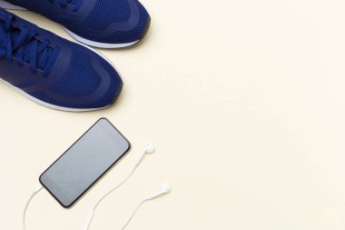 spor ayakkabı ve açık renkli kulaklık ile cep telefonu kapatın 