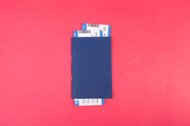 Mavi pasaport üzerinde pembe bir arka plan, üstten görünüm içindeki iki uçak bileti ile