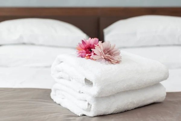 close up of towels and flowers on bed in hotel room