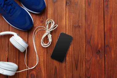 Spor ayakkabı, ahşap masa üzerinde kulaklık ile cep telefonu