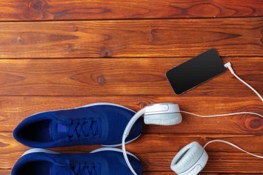 Spor ayakkabı, ahşap masa üzerinde kulaklık ile cep telefonu
