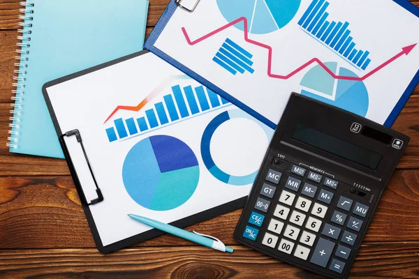 Top view of business paper charts or graphs on wooden table