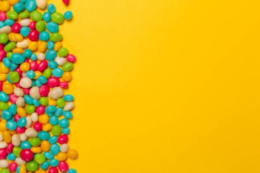 sarı arka plan üzerinde renkli şekerler, üstten görünüm